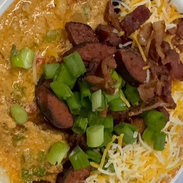Noonie's Place soul food: creamy grits topped with sausage, bacon, shredded cheese, and green onions.